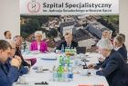 Grupa ludzi debatujących przy stole. 