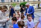 Wicemarszałek Józef Gawron rozdaje drewniane gadżety dzieciom.