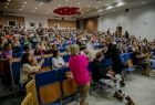 dzieci na widowni oglądające pokaz eksperymentów na scenie.