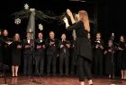 Dyrygentka stoi przed chórem na scenie
