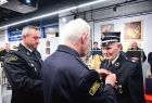 Oficerowie straży pożarnej dekorują odznaczeniem emerytowanego strażaka