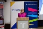 Kobieta w różowej sukience przy mównicy. 