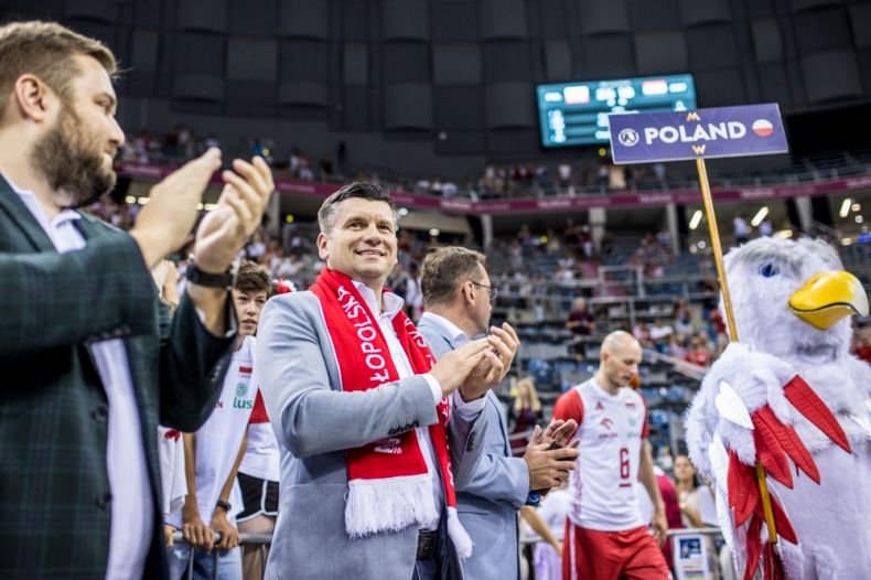Marszałek Łukasz Smółka stoi na płycie areny. Obok przechodzi drużyna z napisem Poland.