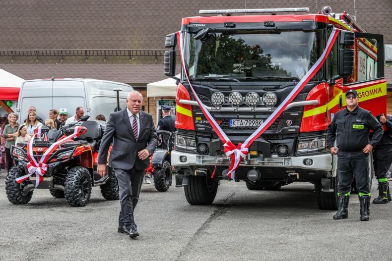 Wicemarszałek Ryszard Pagacz przechodzi obok nowych wozów strażackich.