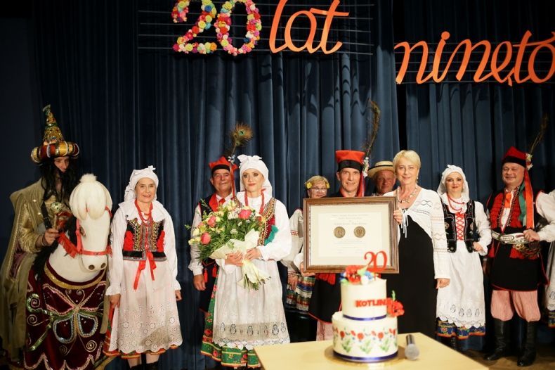 Iwona Gibas z zarządu województwa wraz z członkami osieckiego zespołu Kotlina prezentują na scenie Nagrodę Samorządu Województwa Małopolskiego Polonia Minor