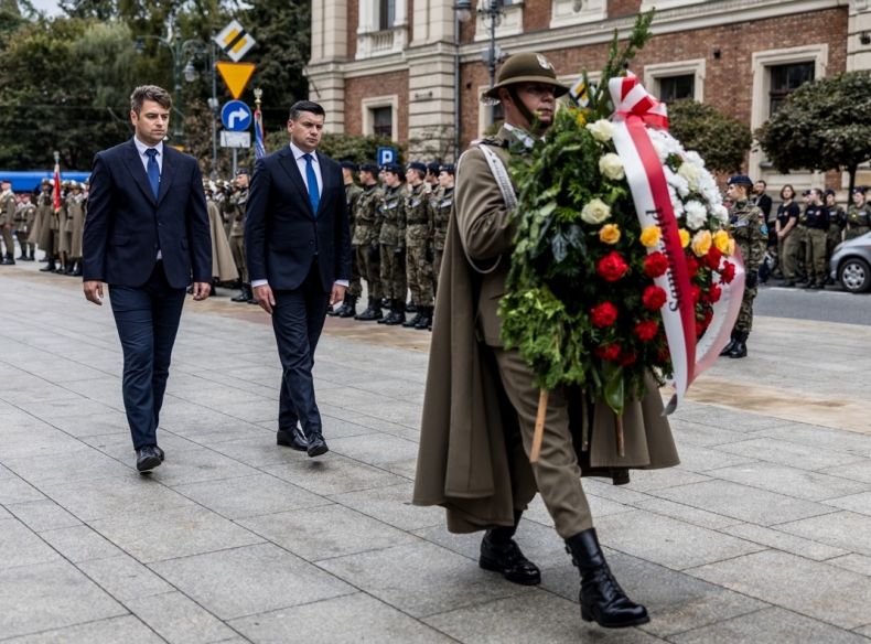 Marszałek Łukasz Smółka i dyrektor Dawid Gleń składają wieniec. Przed nimi idzie żołnierz.