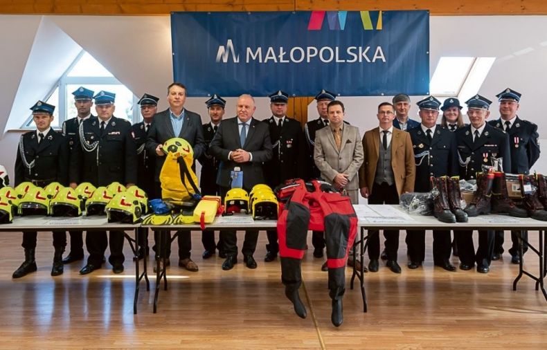 Uczestnicy spotkania stoją na sali. Nad nimi napis Małopolska.