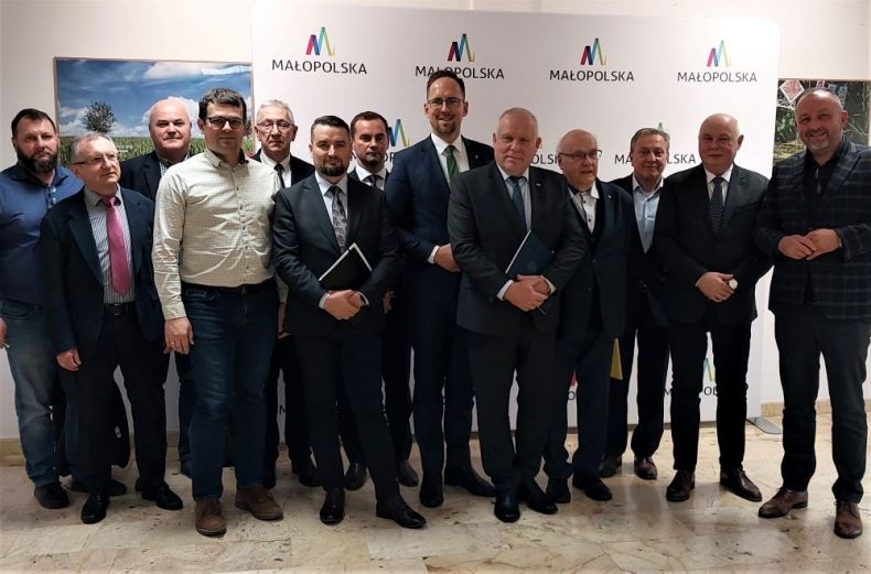 Wicemarszałek Ryszard Pagacz stoi z uczestnikami wydarzenia. Z tyłu widoczna ściana z napisem Małopolska.