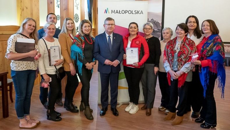 Uczestnicy wydarzenia stoją przed banerem z napisem Małopolska.