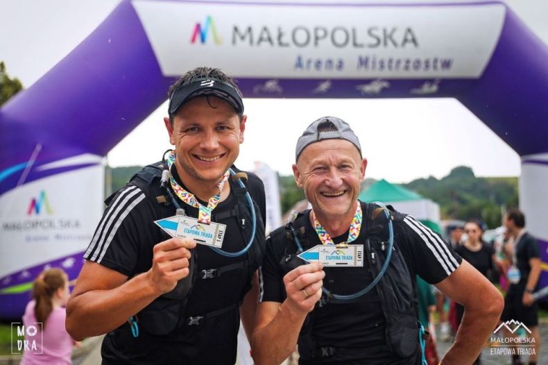 Dwóch biegaczy w rękach trzyma medale.
