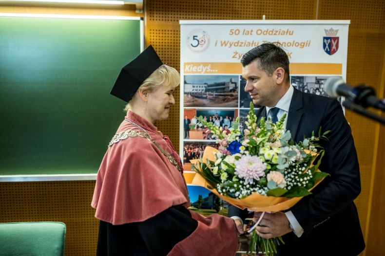 Wicemarszałek Łukasz Smółka wręcza kwiaty kobiecie.