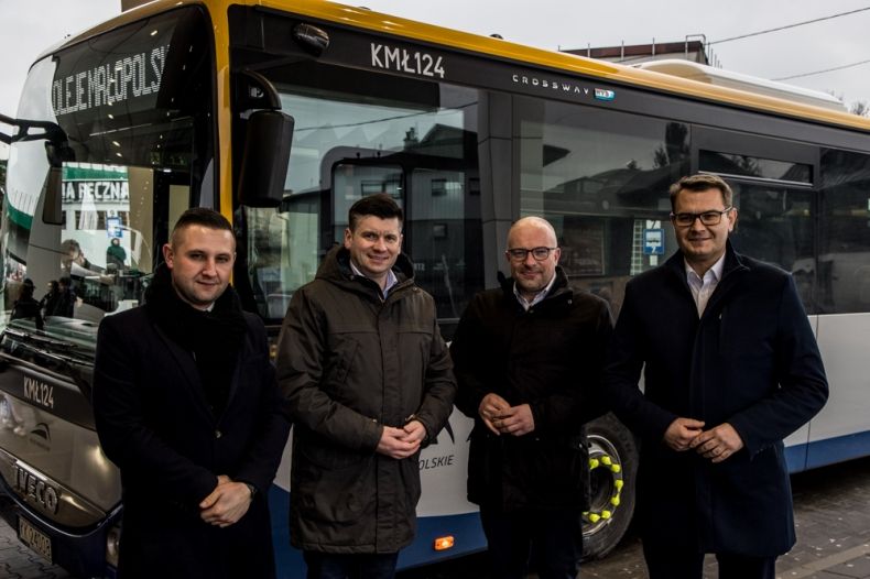 Uczestnicy wydarzenia stoją przed nowym autobusem.