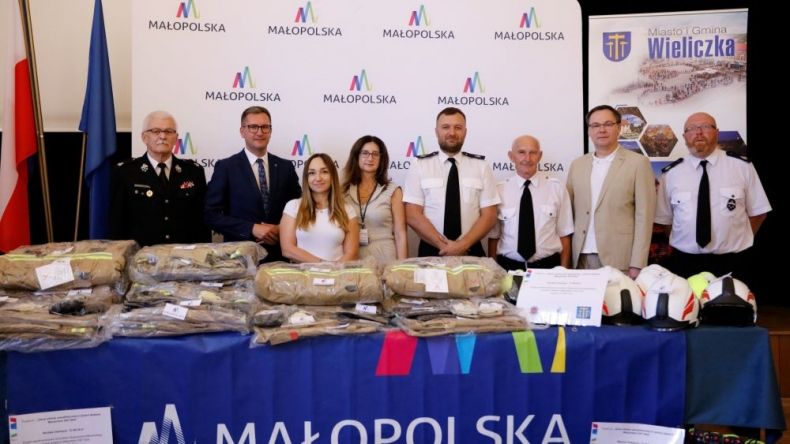 Uczestnicy wydarzenia stoją przed stołem napisem Małopolska.