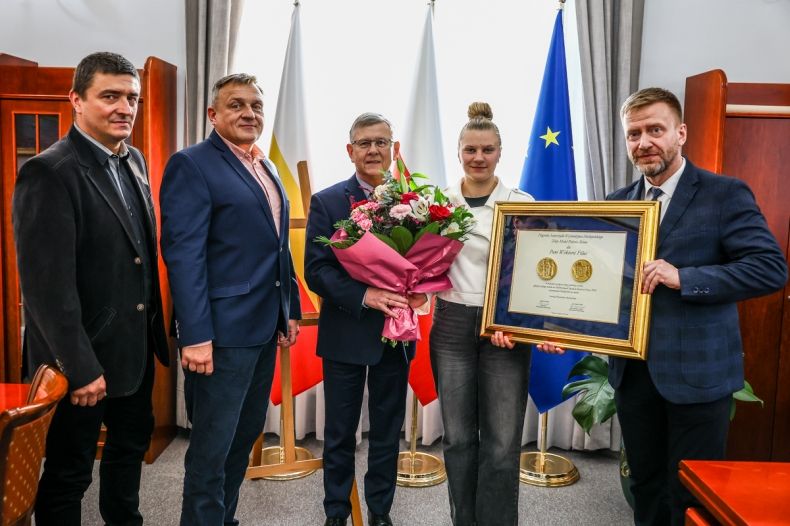 Wicemarszałek Witold Kozłowski oraz radny Mirosław Dróżdż z kwiatami i nagrodą Polonia Minor. Obok trzech mężczyzn. 