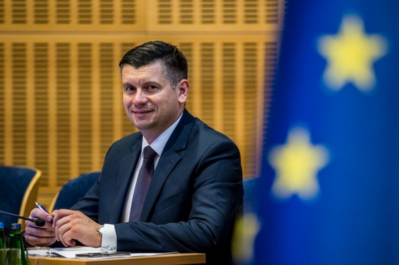 Marszałek Łukasz Smółka siedzi przy stole.