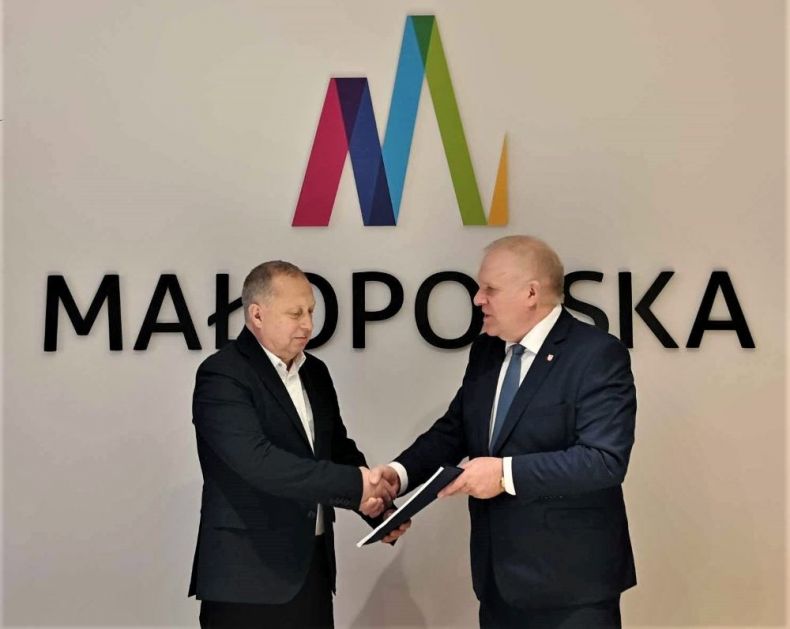 Wicemarszałek Ryszard Pagacz podaje rękę mężczyźnie. Za nimi widoczne logo Małopolska.