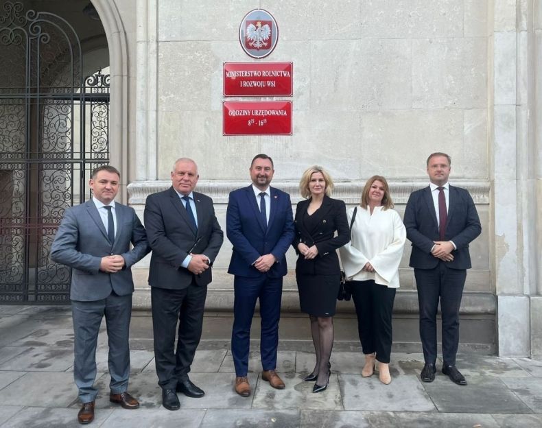 Uczestnicy wydarzenia stoją przed wejściem do budynku ministerstwa.