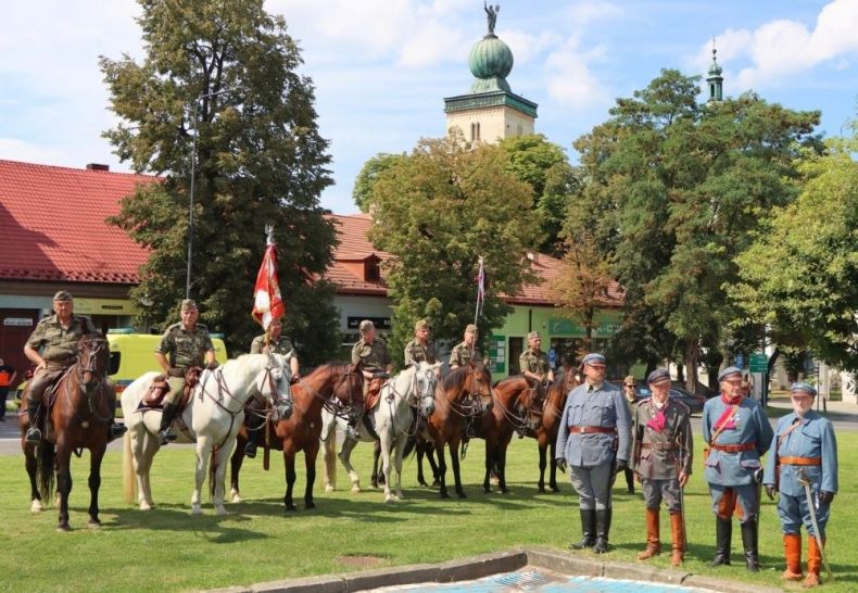 Żołnierze w strojach historycznych i na koniach siedzą na koniach.