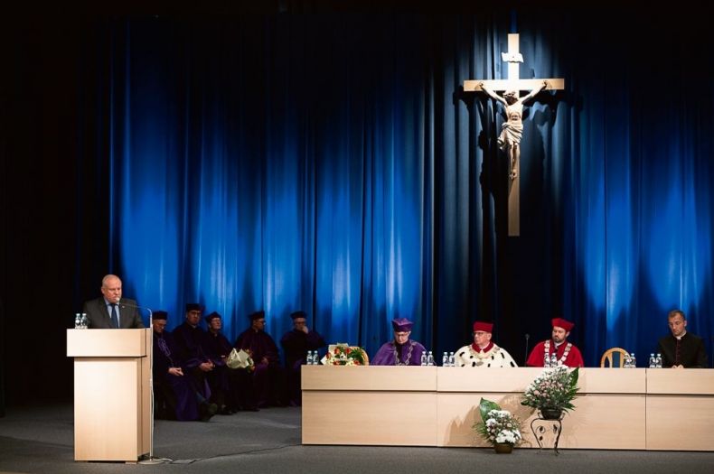 Wicemarszałek Ryszard Pagacz stoi na scenie przy mównicy. Na ścianie wisi krzyż.