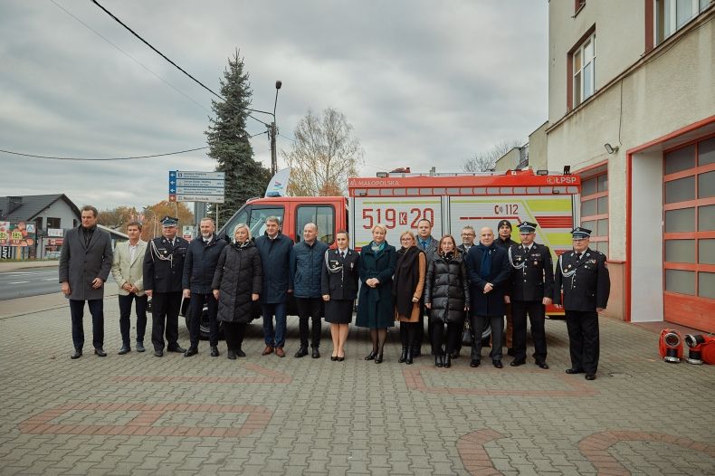 Zdjęcie pamiątkowe z udziałem strażaków i samorządowców, stojących wspólnie przed remizą OSP Oświęcim, z okazji przekazania tej jednostce nowego samochodu ratowniczo-gaśniczego