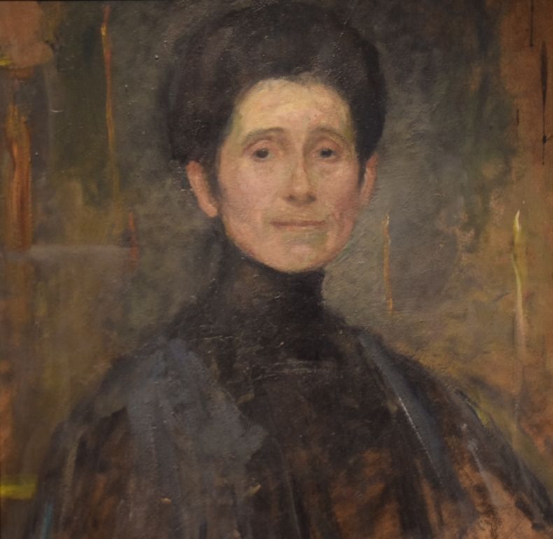 Autoportret Olgi Boznańskiej, kobieta w średnim wieku, ciemne włosy uczesane w ,,koka,, suknie w ciemnych szaro-czarnych barwach, projekt sukni z epoki zakrywa cała szyję 
