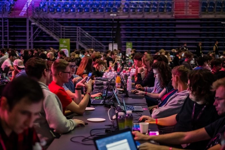 Młodzi uczestnicy hackhatonu siedzą przy stole