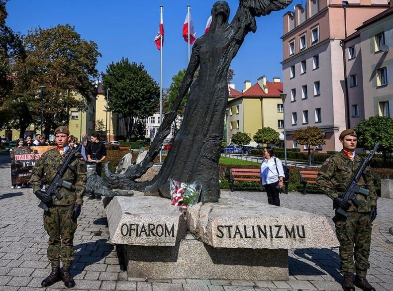 Żołnierze stoją na warcie przed pomnikiem z napisem Ofiarom Stalinizmu.