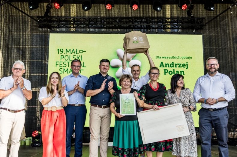 Grupa osób na scenie z nagrodami w ręku.