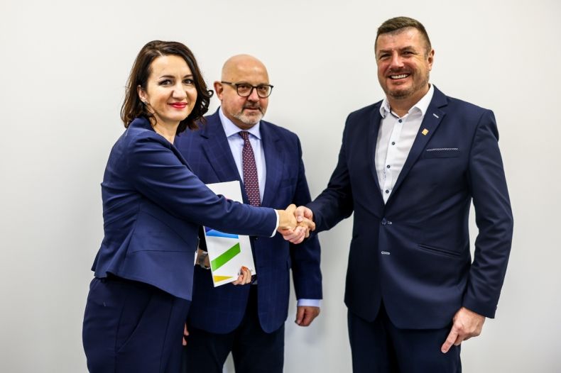 Członek zarządu Marta Malec-Lech w geście uścisku dłoni z mężczyzną w garniturze. 