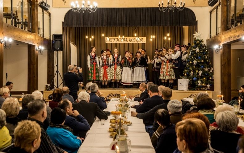 Uczestnicy spotkania świątecznego siedzą przy stole