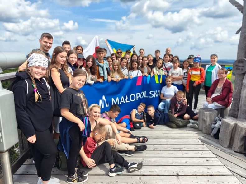 Grupa dzieci z banerem "Małopolska" i flagami Polski i Ukrainy.