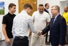 Wicemarszałek Witold Kozłowski podaje dłoń chłopcu w białej koszuli.
