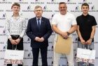 Wicemarszałek Witold Kozłowski z trzema mężczyznami trzymającymi prezenty.