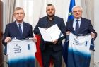 umowa w rękach prezesa oraz koszulki w rękach wicemarszałka i radnego województwa małopolskiego