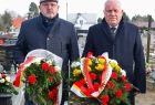 Wicemarszałek Ryszard Pagacz stoi i trzyma kwiaty. Obok stoi inny mężczyzna z kwiatami.