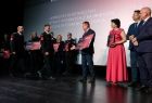 Wicemarszałek Ryszard Pagacz na scenie podczas wręczania nagród. Obok stoją inni ludzie.