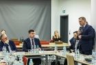 Marszałek Łukasz Smółka siedzi przy stole, obok stoi mężczyzna.