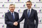 Wicemarszałek Witold Kozłowski w geście uścisku dłoni z mężczyzną w garniturze. 