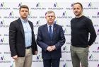 Wicemarszałek Witold Kozłowski i dwóch mężczyzn na tle ścianki reklamowej z napisem Małopolska.