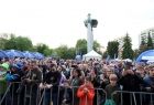 Ludzie stoją na rynku. Widoczny pomnik.