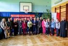 Uczestnicy wydarzenia stoją na sali gimnastycznej w szkole.