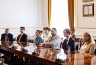 Uczniowie i nauczyciele siedzący przy długim stole.