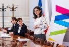 Kobieta stojąca przy stole w trakcie przemowy.