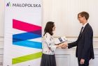 Chłopiec w garniturze w uścisku dłoni z kobietą.