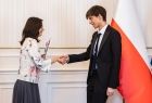 Uczeń w czarnym garniturze odbierający gratulacje.