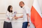Nauczyciel w białej koszuli odbierający gratulacje.