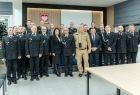 Uczestnicy wydarzenia stoją na scenie w sali.