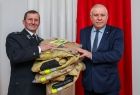 Wicemarszałek Ryszard Pagacz przekazuje strażakowi mundury.
