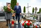 Wicemarszałek Ryszard Pagacz stoi na cmentarzu. Obok kobieta z kwiatami.