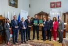 Uczestnicy spotkania stoją razem z gabinecie.